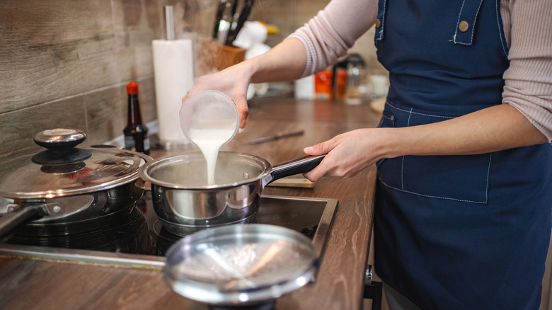 Person pouring milk into saucepan
