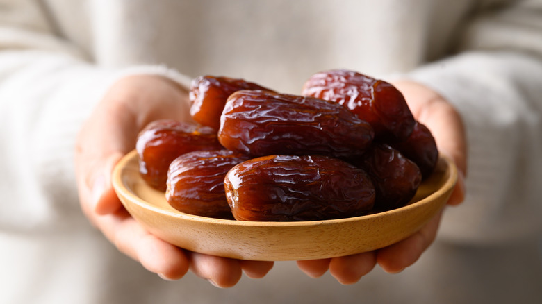Hands holding dish of dates