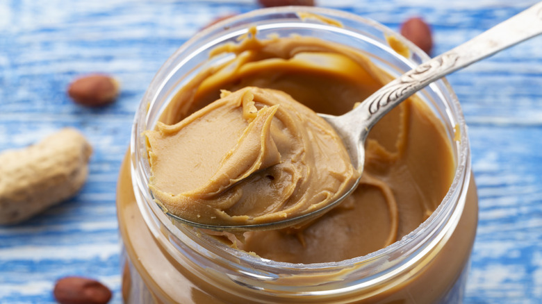 Open jar of peanut butter with spoon