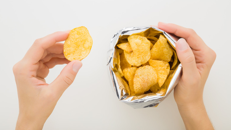 Hands taking chips from bag