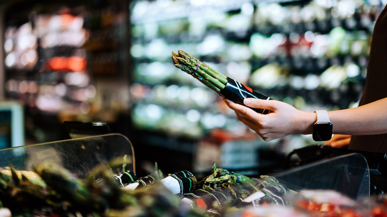 Shopper picking up asparagus in grocery store
