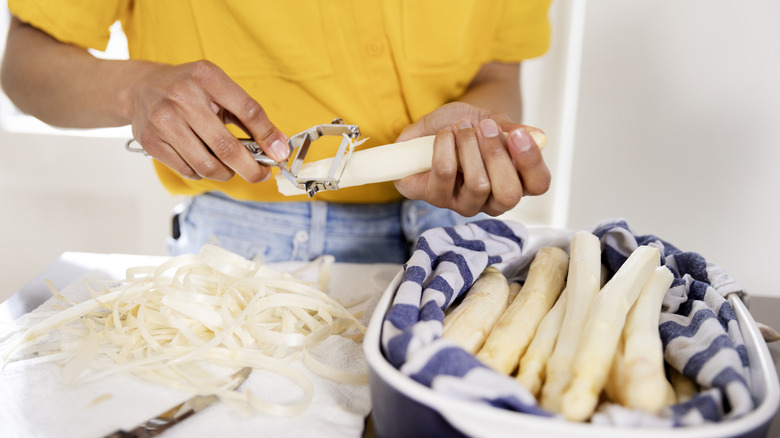 Person peeling white asparagus
