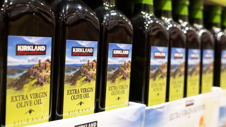 Bottles of Kirkland Extra Virgin Olive Oil on shelves at Costco