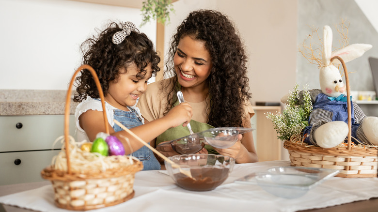 A smiling mom and daughter making homemade treats in a kitchen with Easter decor