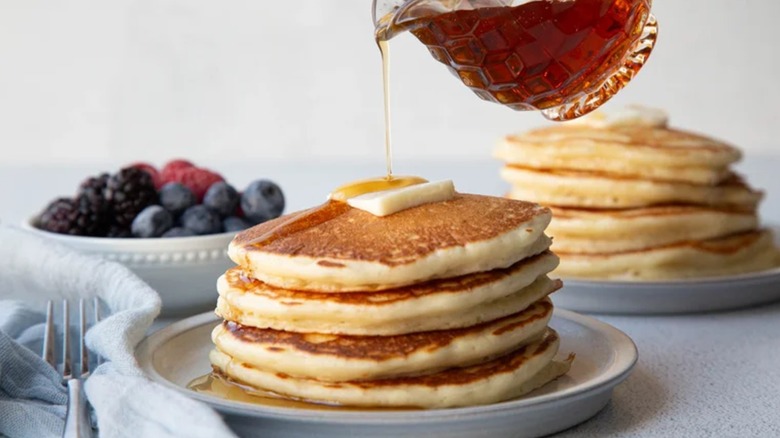 Pouring syrup onto stack of pancakes