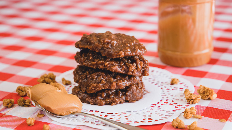 Stack of no-bake cookies next to spoon with peanut butter