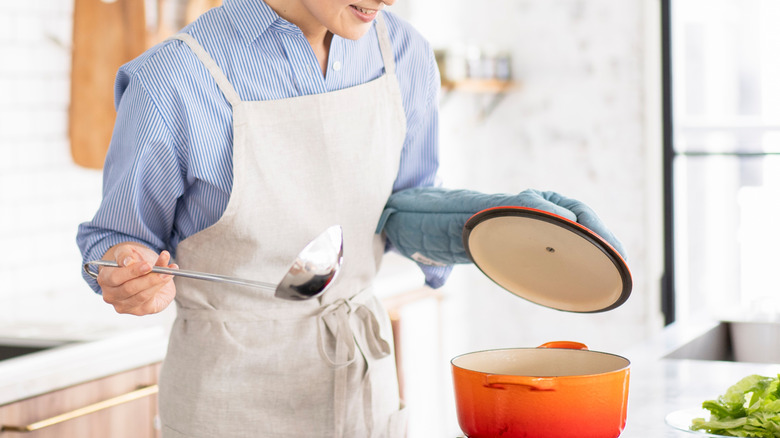 Woman standing over pot in kitchen