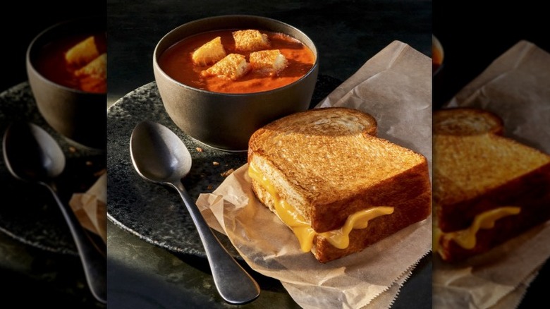 grilled cheese next to a bowl of tomato soup with croutons on top