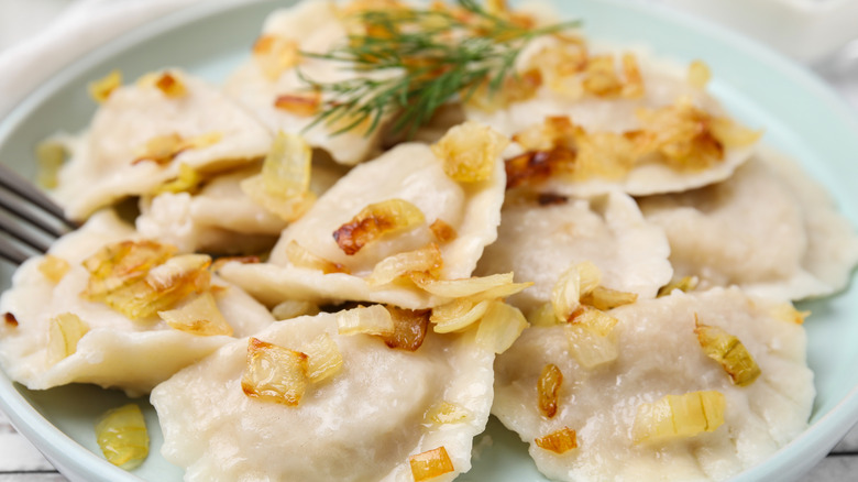 cooked pierogi topped with onions and dill