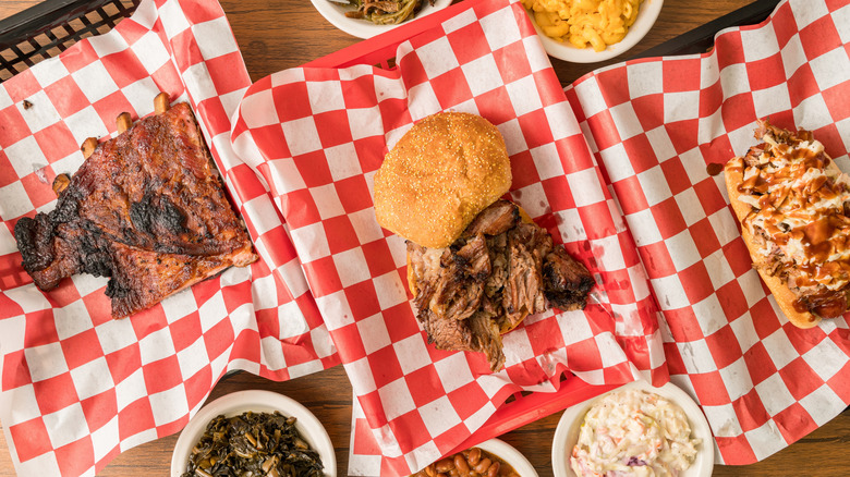 Barbecue ribs, brisket sandwich, pulled chicken sandwich, collard greens, coleslaw, and mac and cheese on red checkerboard paper