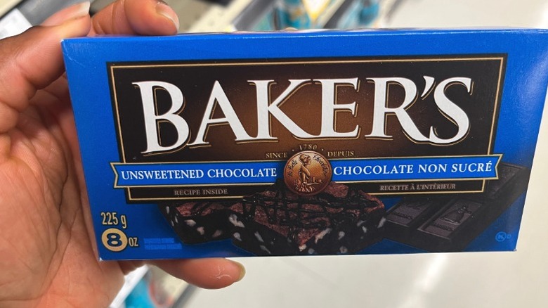 A hand holding a box of Baker's chocolate.
