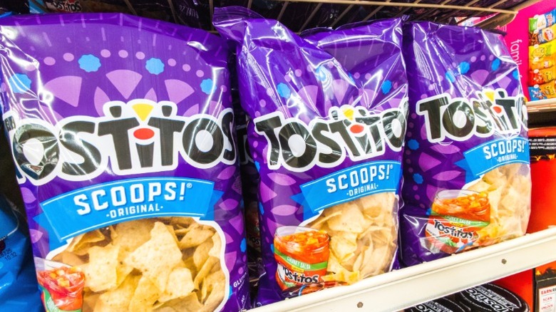 Three bags of Tostitos scoops on a supermarket shelf.