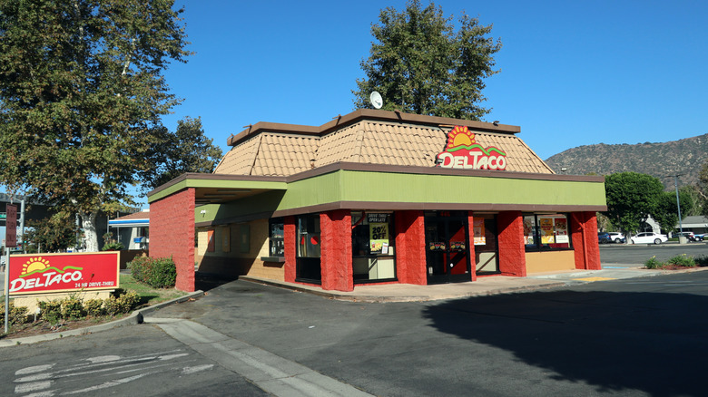 Red and green Del Taco location with rocky hills in the background.