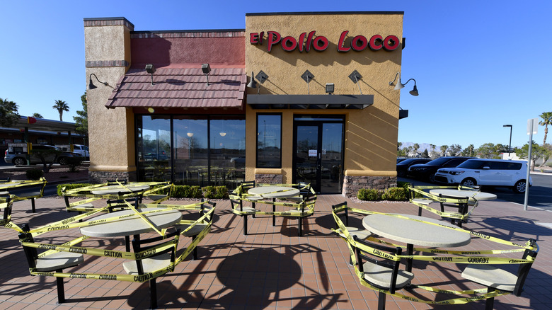 Tables covered in caution tape outside a Pollo Loco.