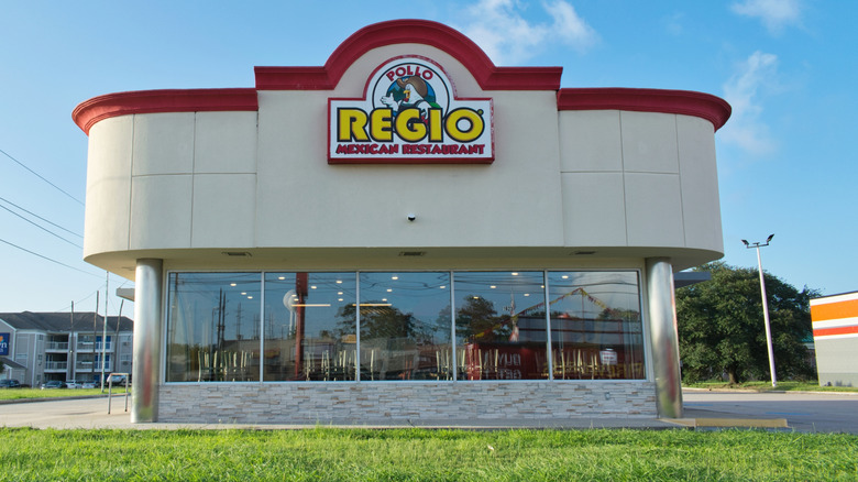 A Pollo Regio in a concrete building with large windows and a red trim.