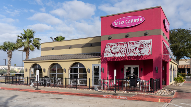 Hot pink and tan Taco Cabana with palm trees nearby.