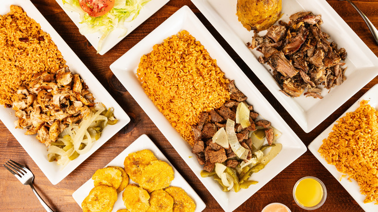 Top down view of several dishes with Puerto Rican, including seasoned rices, and marinated meats