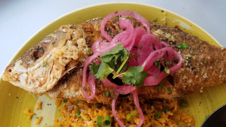 fried fish from Puerto Rico on plate with rice and pickled cabbage