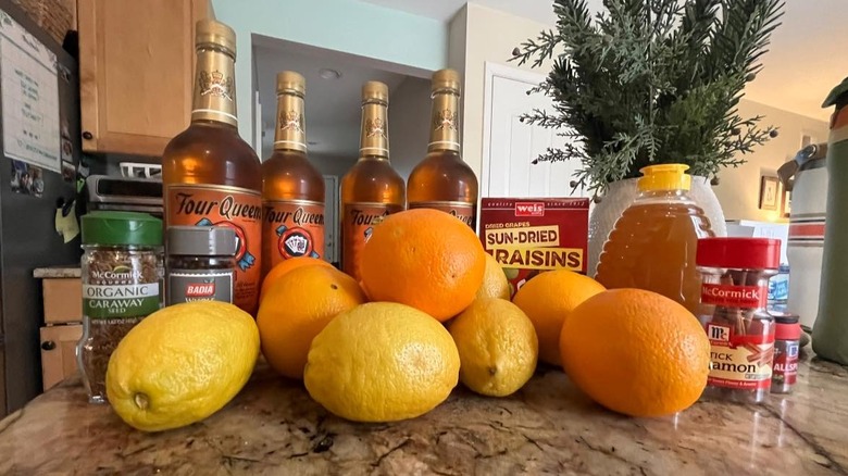 Ingredients for Boilo on countertop including citrus, Four Queens, honey