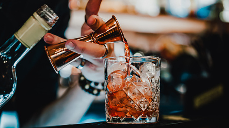 Bartender making a cocktail pouring liquor into glass