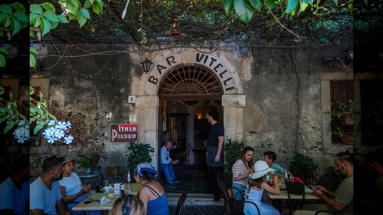 Customers at tables and the stone archway over the door to Bar Vitelli