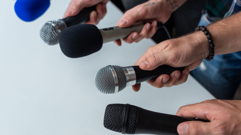 A close-up of hands holding microphones