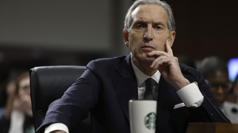 Howard Schulz, former CEO of Starbucks, sitting at a desk with a coffee
