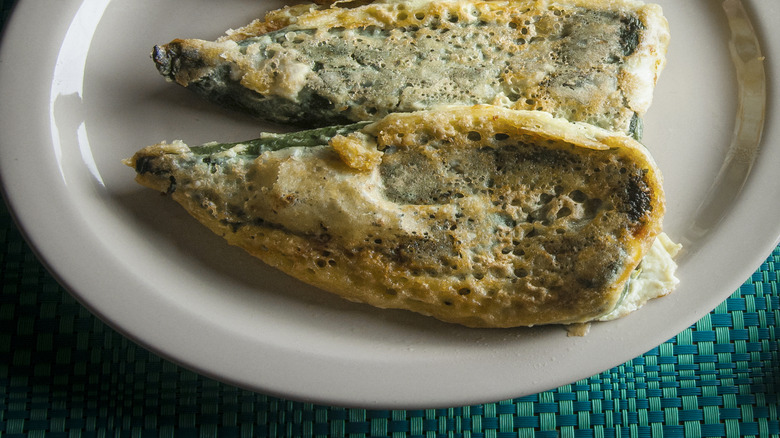 Battered, golden chiles rellenos on a white plate