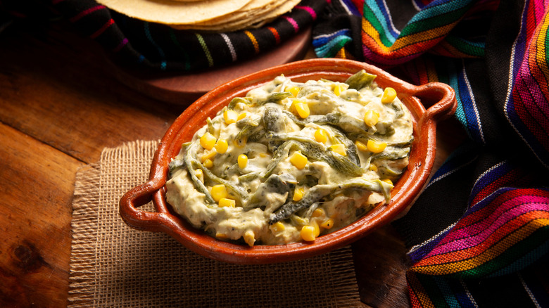 Creamy red clay dish of rajas con crema, with sarape napkin