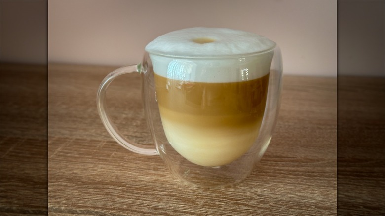 Cold foam on hot coffee latte in a clear glass mug