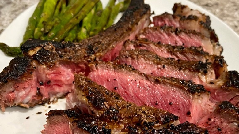 Sliced steak and asparagus on a white plate.
