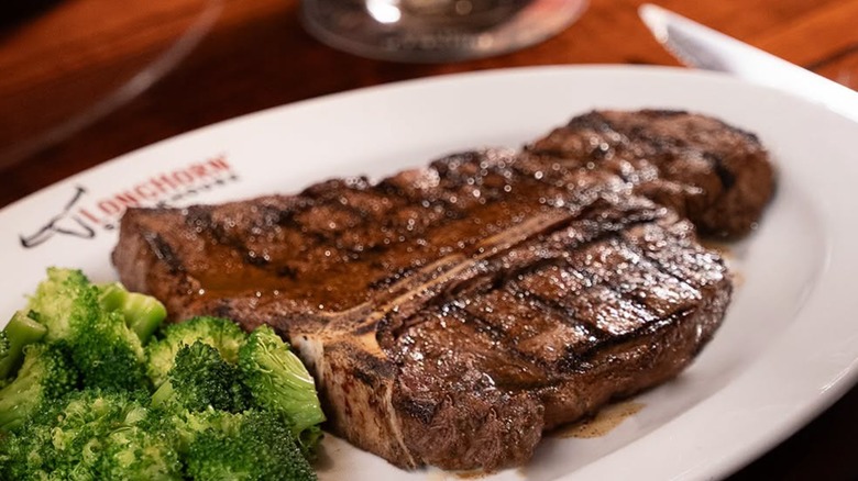 Broccoli and a large steak positioned on a Longhorn Steakhouse-branded plate.