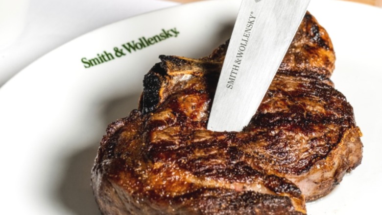 A steak and a Smith & Wollensky-branded knife on a white, oval, Smith & Wollensky-branded plate
