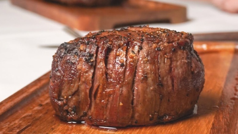 A small, juicy steak on a wooden cutting board.