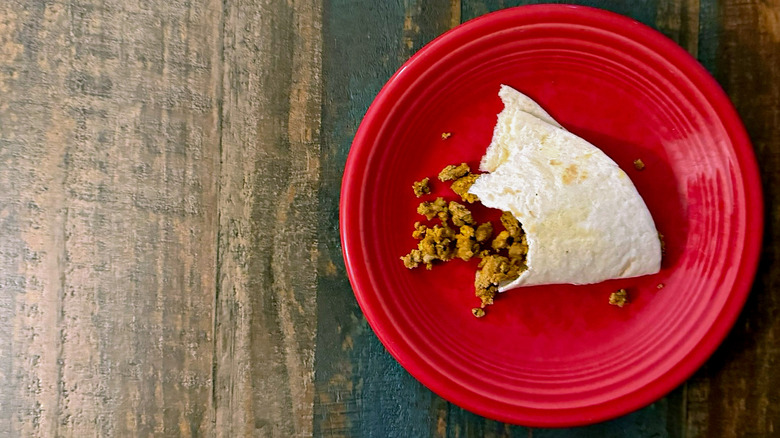 a half eaten soft taco on a plate