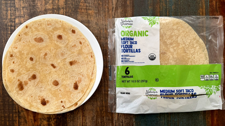 A package of Nature's Promise Organic Soft Flour Tortillas next to a tortilla on a plate