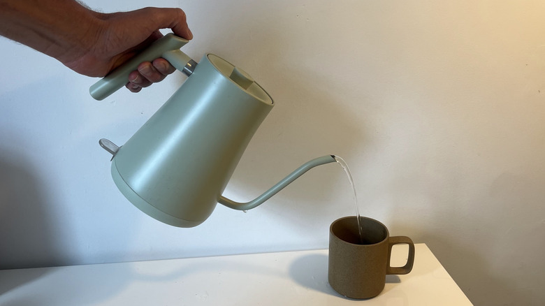 An electric kettle pouring water into a mug