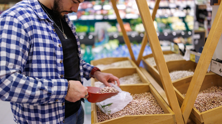 Man scooping beans into bag at grocery store