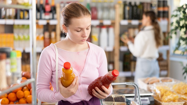 Woman examining two juice bottles at grocery store