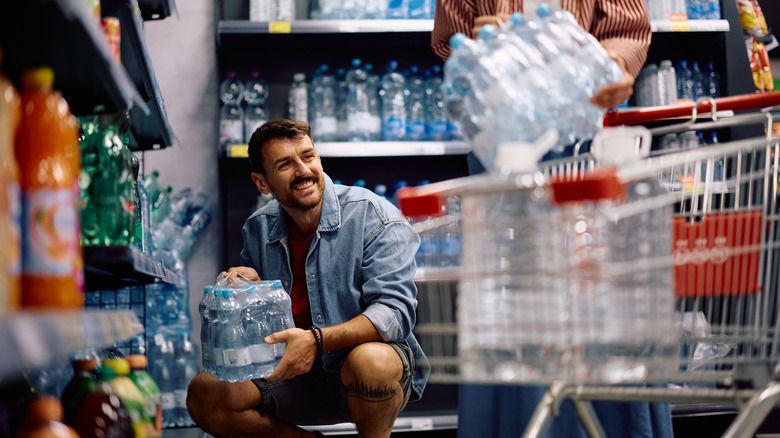 Man pulling water bottles off of shelf