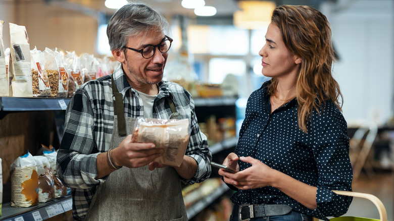 Male supermarket employee assisting a woman customer