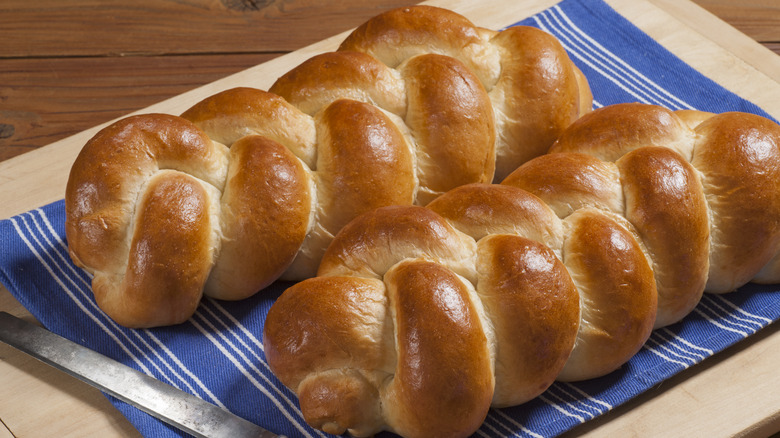 Two loaves of challah bread on blue towel