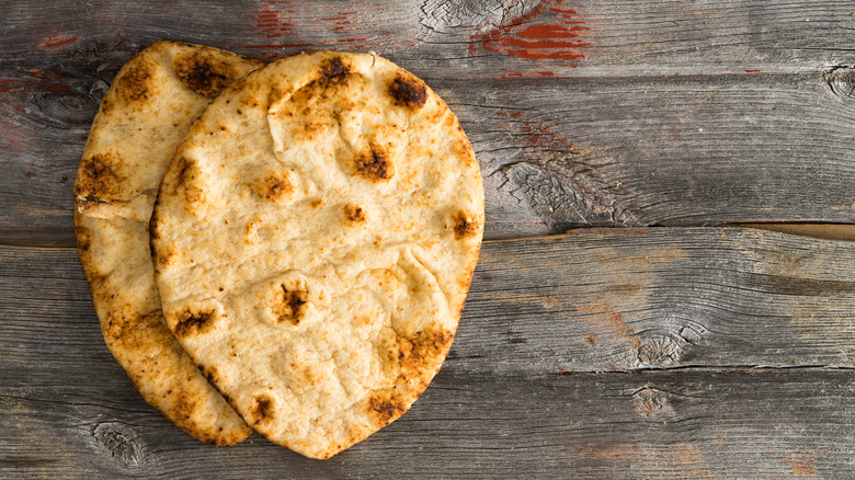 Two pieces of flatbread on wooden surface