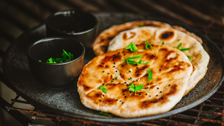 Naan bread on dark gray plate with herbs