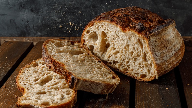 Rustic artisan bread loaf sliced on wooden surface