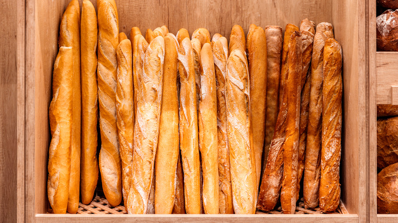 Upright stacks of baguettes on wooden shelf