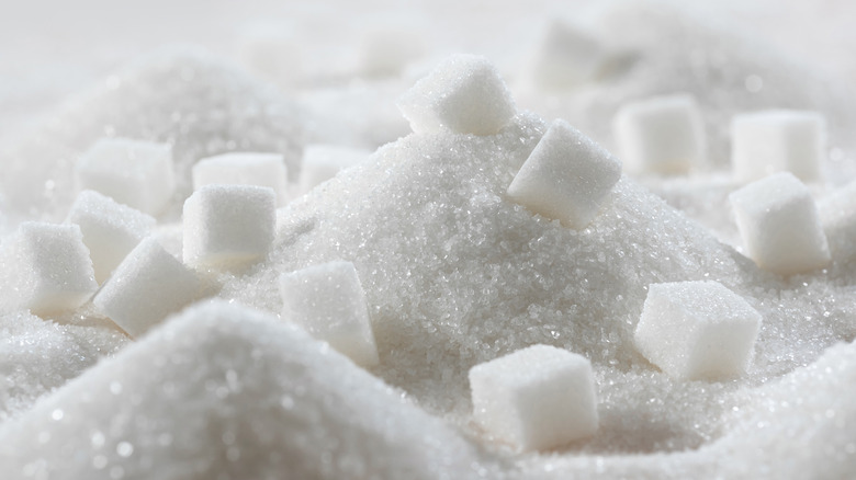 White granulated sugar and sugar cubes piled on a table.