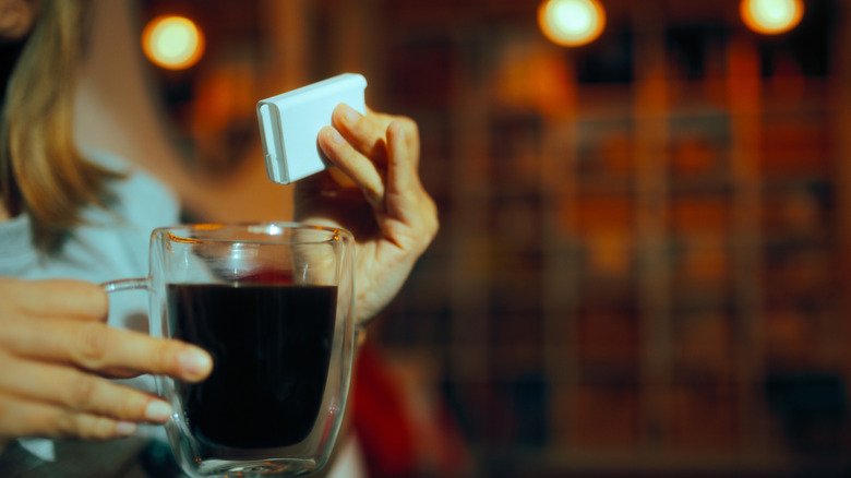 A woman adding sugar to her coffee.
