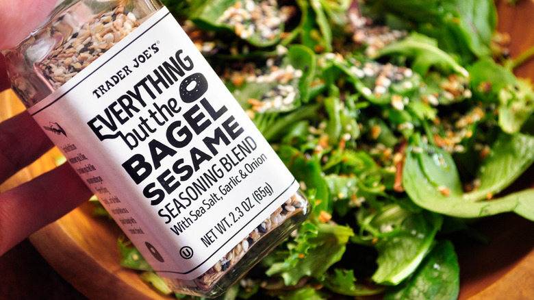 Bottle of Trader Joe's Everything But The Bagel Seasoning  with greens in the background