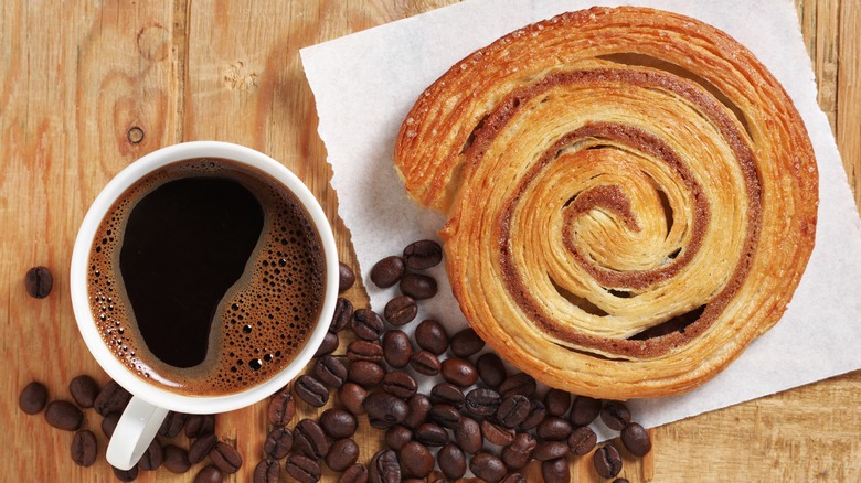 Plain cinnamon roll and cup of coffee on wooden table